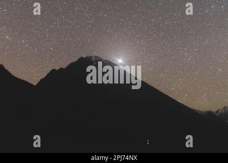 Stella luminosa Sirius su una montagna con ghiacciai di notte con la luce di un parcheggio turistico sulla riva di un lago in Altai Foto Stock
