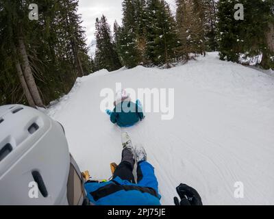 Punto di vista di un pilota che si diverte su una slitta da neve cercando di catturare sua figlia. Foto Stock