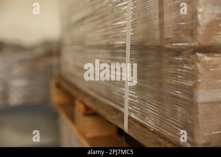 Pile di merce avvolte in film estensibile su pallet di legno, primo piano Foto Stock