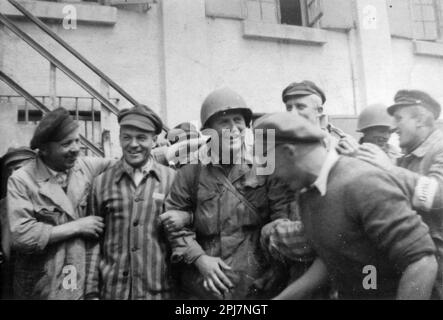 Un soldato americano è circondato dai sopravvissuti nel campo di concentramento di Dachau, appena liberato, il 29 aprile 1945 a Dachau, Germania. I soldati americani dell'esercito statunitense del 7th, compresi i membri della fanteria del 42nd, della fanteria del 45th e delle Divisioni corazzate del 20th, hanno partecipato alla liberazione del campo. Foto Stock