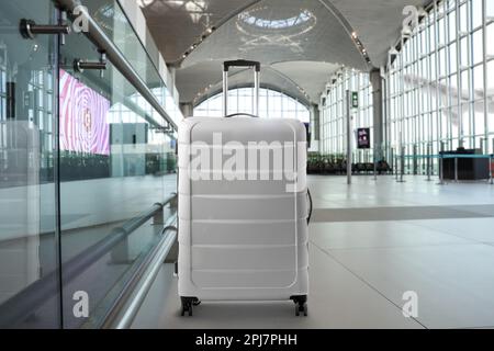 Elegante valigia grigio chiaro nel terminal dell'aeroporto Foto Stock