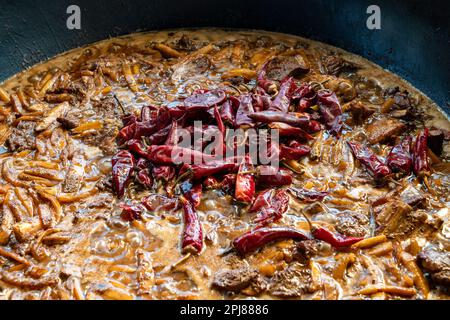 Cialde di pepe rosso caldo in carne bollita con verdure. Una delle fasi di cottura del pilaf uzbeko. Cucina tradizionale nazionale dell'Uzbekistan Foto Stock