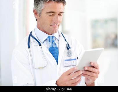 I miei pazienti vengono sempre per primi. un medico che tiene un tablet digitale mentre si trova in un corridoio ospedaliero. Foto Stock