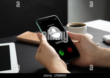 Donna che decide di rispondere alla chiamata in arrivo da un chiamante sconosciuto o di non essere al tavolo, primo piano. Attenzione - frode Foto Stock