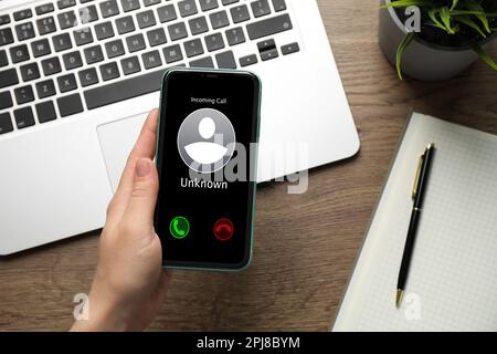 Donna che decide di rispondere alla chiamata in arrivo da un chiamante sconosciuto o di non essere al tavolo, primo piano. Attenzione - frode Foto Stock