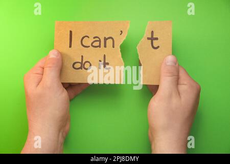 Uomo strappare la carta facendo frase posso farlo su sfondo verde, vista dall'alto Foto Stock