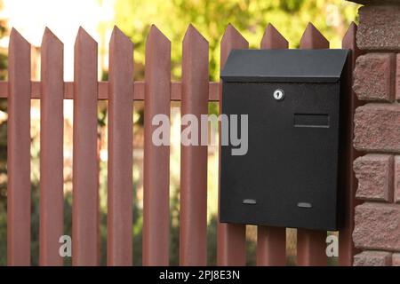 Cassetta per lettere in metallo nero su recinzione all'aperto Foto Stock