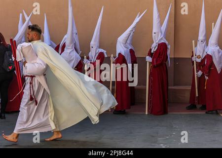 Malaga, Spagna. 31st Mar, 2023. I partecipanti si allineano per una processione della settimana Santa nel quartiere di Dos Hermanas a Malaga, Spagna. La processione fu aperta dalla croce guida scortata da lanterne e seguita da file di Nazareni che portavano candele rosse. In comune con altri eventi della settimana Santa in Spagna, alcuni partecipanti alla processione usano un vestito nazareno o penitenziale. Questo indumento è costituito da una tunica e da un capirote (cappuccio con punta conica) utilizzati per nascondere la faccia dell'indossatore. (Credit Image: © Lorenzo Carnero/ZUMA Press Wire) SOLO PER USO EDITORIALE! Non per USO commerciale! Foto Stock