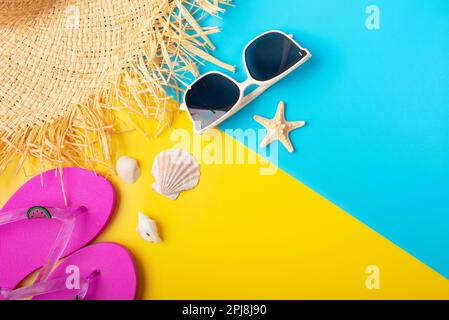 Cappello di paglia sunglesses infradito e conchiglie su sfondo giallo e blu vacanza pianificazione del viaggio mockup Foto Stock
