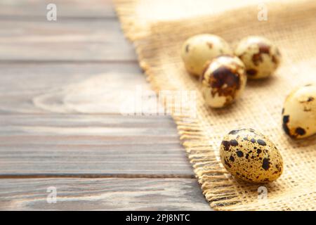 Molte uova di quaglia con sackcloth su fondo marrone. Vista dall'alto Foto Stock