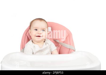 Ragazza felice del bambino seduta in un sorriso della sedia alta isolato su sfondo bianco Foto Stock