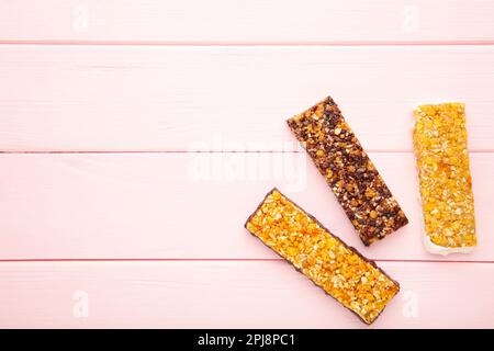 Snack sano, barrette muesli con uva passa e bacche secche su sfondo rosa con spazio copia. Vista dall'alto Foto Stock