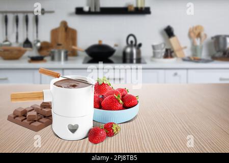 Fonduta con cioccolato e fragole fresche su tavolo in legno in cucina. Spazio per il testo Foto Stock