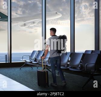 Uomo con valigia e zaino nell'area d'attesa dell'aeroporto Foto Stock