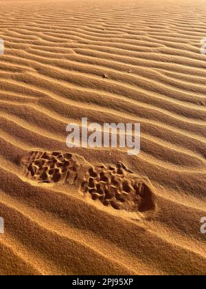 Stampa di scarpe su una duna di sabbia nel deserto del Sahara, Merzouga. Grani di sabbia che formano piccole onde sulle dune. Tramonto. Marocco Foto Stock