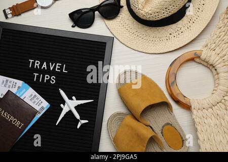 Lavagna a lettere nera con frase Consigli di viaggio e oggetti turistici su tavola di legno bianco, piatto Foto Stock