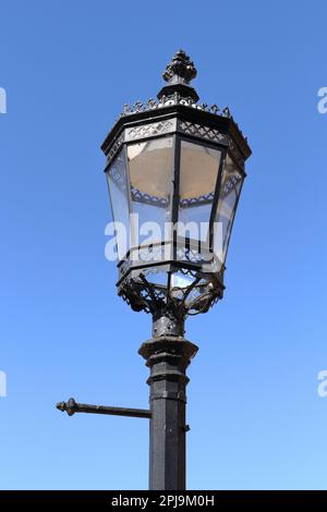 Luce stradale vittoriana in ghisa contro un cielo blu Foto Stock