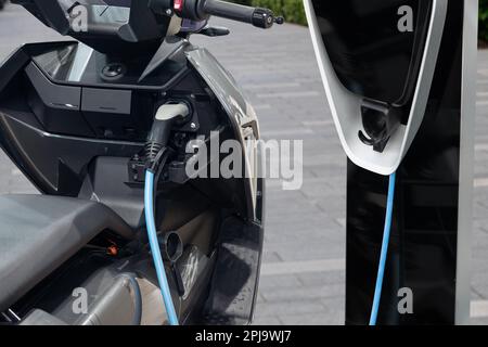 Scooter elettrico con stazione di ricarica su una strada cittadina. Foto di alta qualità Foto Stock