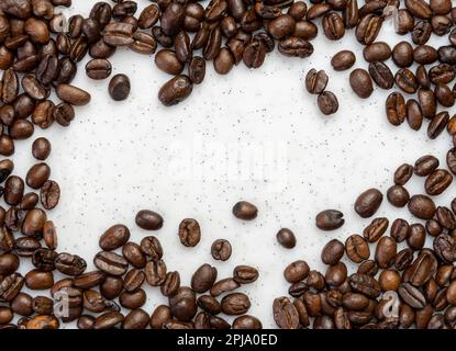 Chicchi di caffè arrostiti che fanno un contorno su un asse bianco Foto Stock