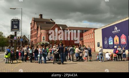 Persone che aspettano fuori dalla fabbrica di birra Northgate di Wadworth/centro visitatori a Devizes per l'arrivo dei loro cavalli shire. Foto Stock