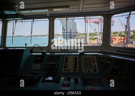 Vista dal ponte del capitano della nave portarinfuse all'ormeggio per carichi sfusi. Vista del terminal del porto dall'interno del ponte del capitano durante il giorno Foto Stock