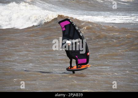 Un surfista alare scivola attraverso un mare mosso alimentato da una brezza rigida al largo della costa Jurrasic nella baia di Lyme. Dorset.UK Foto Stock