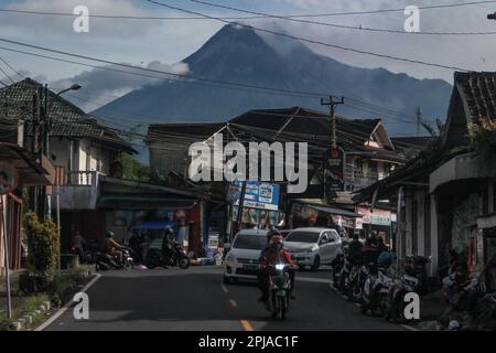 Sleman, Yogyakarta, Indonesia. 1st Apr, 2023. I motociclisti passano sullo sfondo del Monte Merapi a Sleman, Yogyakarta, Indonesia, sabato 1 aprile, 2023. Il monte Merapi è a un livello allerta e spesso emette nuvole calde e lava incandescente verso i fiumi Bebeng, Krasak e Boyong per un livello pericoloso a una distanza da 5 a 7 chilometri dalla cima del monte Merapi. (Credit Image: © Slamet Riyadi/ZUMA Press Wire) SOLO PER USO EDITORIALE! Non per USO commerciale! Foto Stock