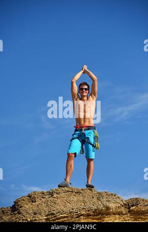 Maschio arrampicatore alzando le mani sulla cima della montagna. Concetto di successo Foto Stock