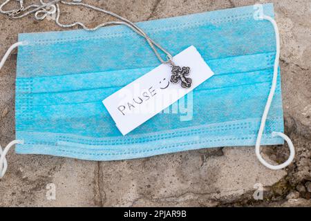 Maschera medica croce d'argento e la parola pausa in inglese è scritto su un pezzo di carta Foto Stock