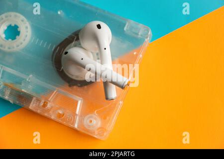 vecchia cassetta musicale e cuffie wireless su sfondo isolato Foto Stock