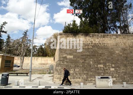 Nicosia, Nicosia, Cipro. 1st Apr, 2023. Un uomo cammina sotto le bandiere della Turchia e della cosiddetta "Repubblica turca di Cipro del Nord”, vicino alla porta di Paphos. Il ministero degli Affari esteri di Cipro ha rilasciato una dichiarazione relativa alle opere all'interno della zona cuscinetto, dove la cosiddetta "Repubblica turca di Cipro del Nord” sta costruendo uno stadio di calcio. La zona cuscinetto è il suolo cipriota che viene donato volentieri alle Nazioni Unite per facilitare il suo dovere di mantenimento della pace e, secondo la dichiarazione, il governo cipriota non ha mai concesso alcuna autorizzazione per lavori all'interno della zona cuscinetto e chiede all'UNFICYP di agire Foto Stock