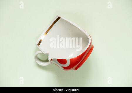 tazza rotta primo piano su sfondo luminoso isolato, piatti rotti Foto Stock