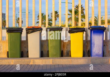 Bidoni multicolore per la raccolta di rifiuti in metallo per la raccolta di diversi tipi di rifiuti su una strada cittadina. Row, gruppo di molti rifiuti dumster all'aperto. Rifiuti ecologici con Foto Stock