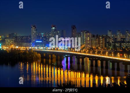 Kiev, Ucraina - 21 maggio 2015: Pittoresco paesaggio urbano notturno del fiume Dnieper e del Ponte di Paton sullo sfondo di alti edifici nel Foto Stock