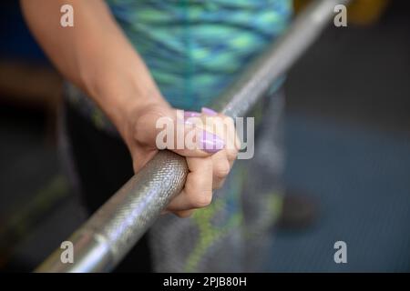 Primo piano della mano di una donna aggrappata a un barbell di metallo per esercizi Foto Stock