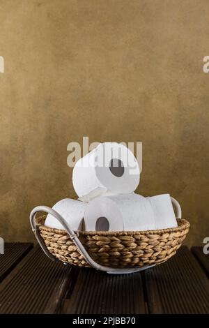 Rotoli di carta igienica nel cesto sullo sfondo di legno Foto Stock