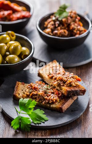 Crostini croccanti con tapenade e ingredienti. Tapenade - deliziosa pasta di olive dalla Francia Foto Stock
