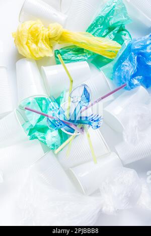 Assortimento di plastica monouso, tazze, posate, sacchetti e cannucce per bevande. Concetto ambientale. Rifiuti non compostabili Foto Stock