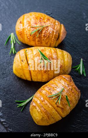 Patate Hasselback. Patate a dorso di Svezia con aglio ed erbe alla griglia nel forno Foto Stock