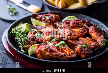 Ali di pollo arrosto in salsa al barbecue con lime e cotto al forno patate in padella rustica Foto Stock