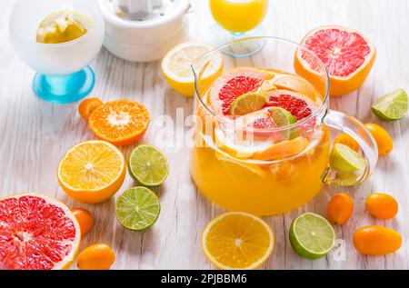 Tè ghiacciato o limonata preparati al momento con agrumi assortiti su sfondo di legno Foto Stock