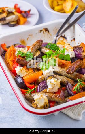 Salsicce arrosto con verdure e formaggio feta in casseruola Foto Stock