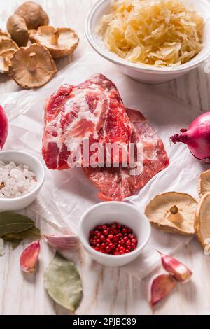 Ingredienti per zuppa di cavolo acida (zuppa di crauti) con carne, cipolla, aglio e speziate su tavola di legno Foto Stock