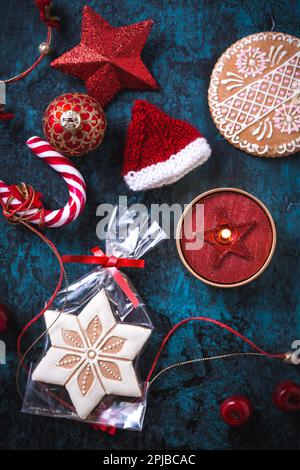 Candela di Natale con biscotti di pan di zenzero, decorazioni e ornamenti su sfondo blu Foto Stock