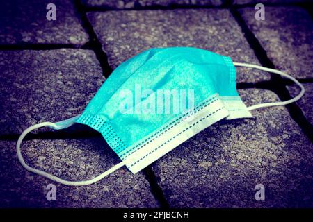 Una maschera usata si trova sul marciapiede Foto Stock