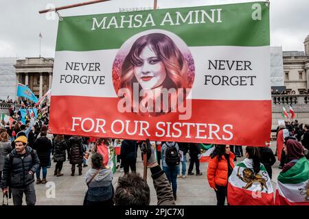 Un banner raffigurante un ritratto di Masha Amini che è morto in custodia della polizia a Teheran per presunta violazione delle regole di copertura dell'hijab nel settembre 2022 è tenuto in alto durante le proteste contro il governo iraniano. Londra, Regno Unito Foto Stock