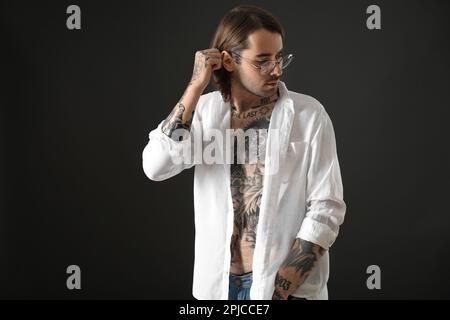 Giovane uomo con tatuaggi sul corpo su sfondo nero Foto Stock