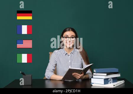 Ritratto dell'insegnante di lingue straniere a tavola di legno e diverse bandiere di lavagna verde Foto Stock