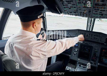 Pilota in abbigliamento formale siede nel pozzetto e controlla l'aereo Foto Stock