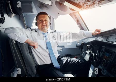 Pilota in abbigliamento formale siede nel pozzetto e controlla l'aereo Foto Stock